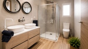 A modern bathroom with two sinks, a glass shower enclosure, a toilet, and a potted plant. - Adela House (Maracena)