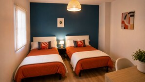 A room with two beds, a desk, a chair, a lamp, and a wall art piece. - Adela House (Maracena)