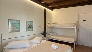 Ein Schlafzimmer mit Holzboden, zwei Betten, einer Tür und zwei gerahmten Bildern an der Wand.