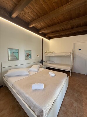 A bedroom with a wooden ceiling, two beds, a door, and two framed pictures on the wall. - IPANEMA FAMILY CLUB DIAMANTE - ROOM 1 (Diamante)