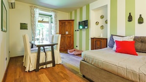 Ein Zimmer mit einem Bett, einem Tisch, Stühlen, einem Holzschrank, einem Fernseher und einem Fenster mit Vorhängen.