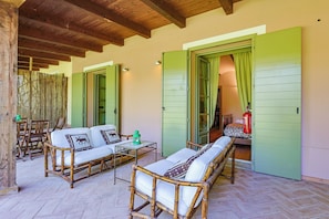 Una habitación con techo de madera, contraventanas verdes, un conjunto de sofá, una mesa con una linterna y un extintor.