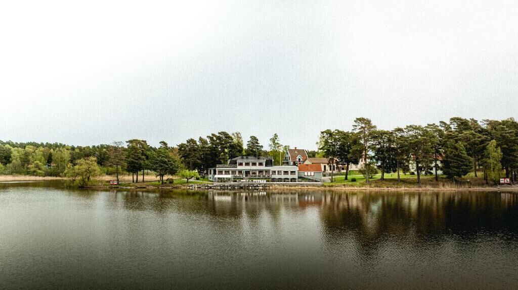A lakeside property with a large house, dock, and surrounding trees.