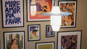 A wall with various framed artworks, including a poster with the text 'EAT SPAGHETTI' and 'MORE AMOR POR FAVOR'. - Fagerudd (Enköping)
