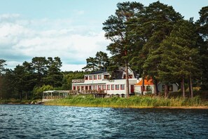 Ein Haus am See mit einer großen Terrasse, umgeben von Bäumen.
