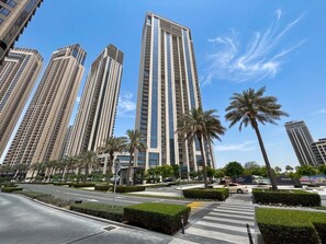 A modern urban area with high-rise buildings, palm trees, and a pedestrian crossing. - Luxury 3BR with Sea Views & Pool - Creekside (Dubai)