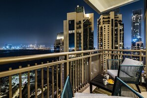 A balcony with a city view, a table with a cup and a plate, and a chair. - Luxury 3BR with Sea Views & Pool - Creekside (Dubai)