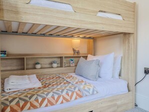 Ein Etagenbett mit unterem Bett, einem Regal mit Dekoration und einer Wandlampe.