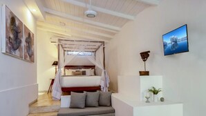 A bedroom with a bed, a sofa, a TV, and a staircase. - The Well House Galle offers a peaceful tropical villa stay in Unawatuna. (Unawatuna)