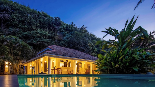 Una casa con piscina, rodeada de vegetación tropical.
