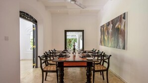 A dining area with a large table, chairs, and a ceiling fan. - The Well House Galle offers a peaceful tropical villa stay in Unawatuna. (Unawatuna)