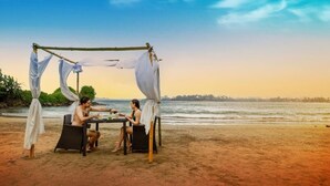 A beachside dining setup with a canopy, two wicker chairs, and a table. - The Well House Galle offers a peaceful tropical villa stay in Unawatuna. (Unawatuna)