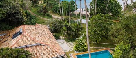 A house with a tiled roof, a swimming pool, and a view of the sea.