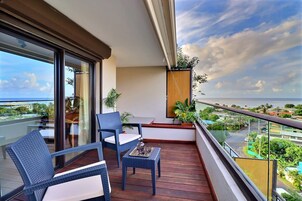 A balcony with wicker furniture, a glass table, and potted plants.