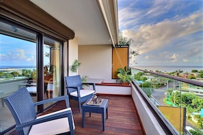 A balcony with wicker furniture, a small table with a tray, and potted plants. - Mahana Suite (Papeete)