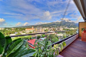Un balcon offrant une vue sur le paysage urbain, avec des bâtiments et des montagnes en toile de fond.
