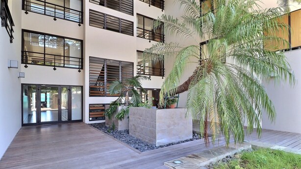 A multi-level building with balconies, large windows, and indoor plants. - Mahana Suite (Papeete)