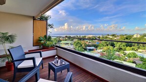A balcony with a wicker chair, a small table, and potted plants. - Mahana Suite (Papeete)