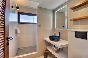 A modern bathroom with a bathtub, a sink with a blue basin, a mirror, and a window. - Mahana Suite (Papeete)