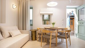 A living room with a sofa, wooden chairs, a round table, and a hanging light fixture. - CF Elegant Old Town Suite Fortezza View (Rethymno)