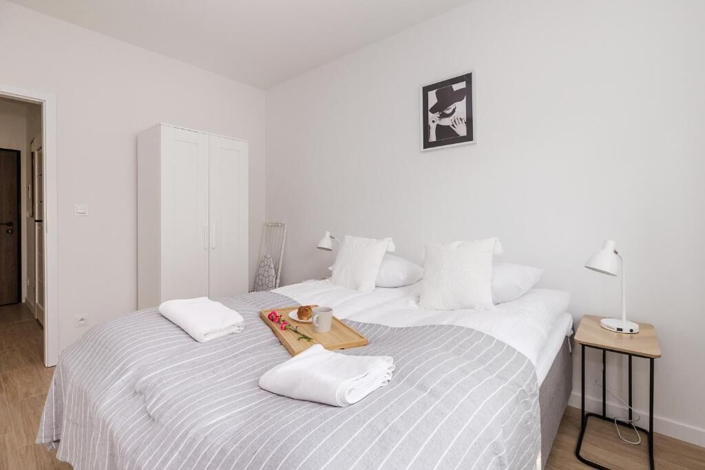 A hotel room with a bed, a wardrobe, a bedside table with a lamp, and a framed picture on the wall.