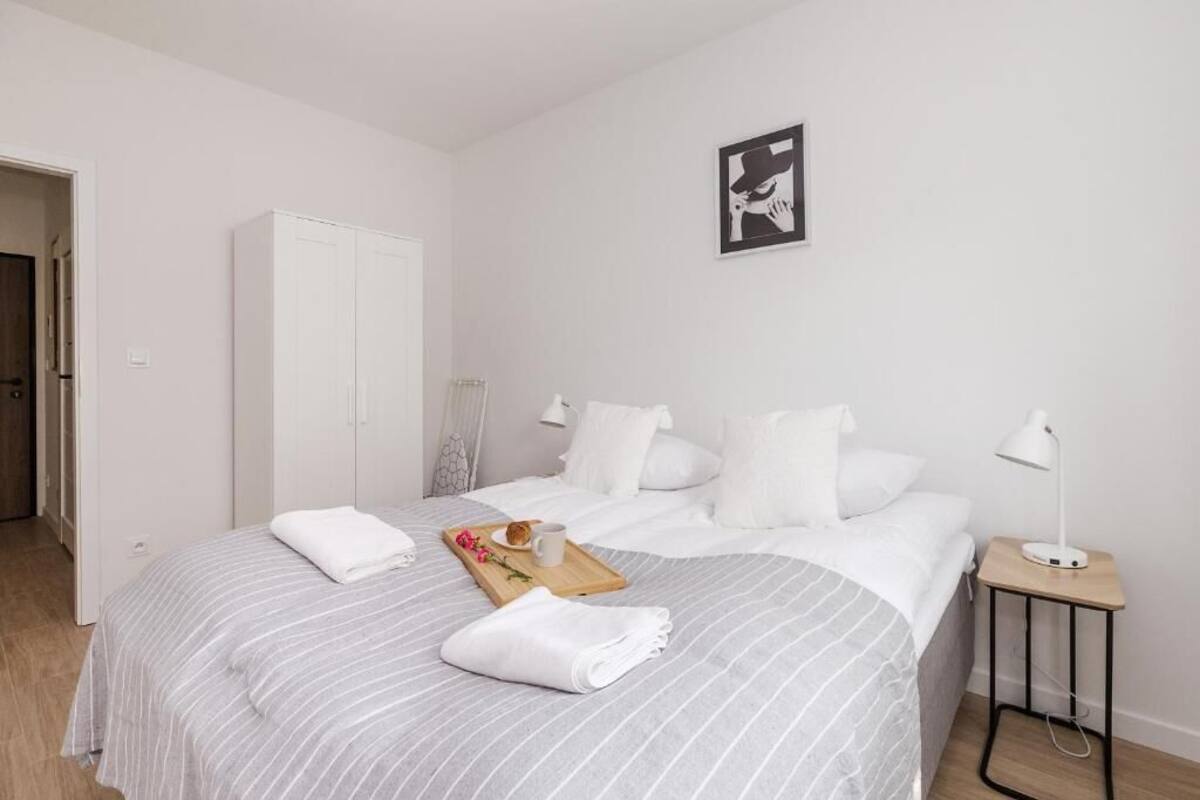 A hotel room with a bed, a wardrobe, a bedside table with a lamp, and a framed picture on the wall.