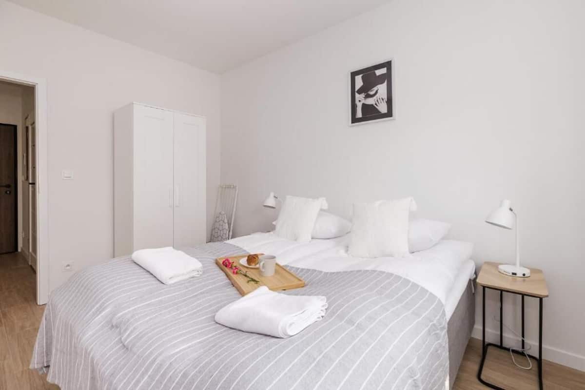 Et hotelværelse med seng, garderobeskab, natbord med lampe og et billede i ramme på væggen.