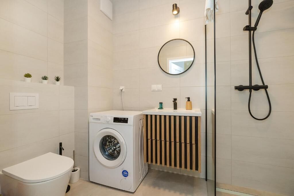 Ein modernes Badezimmer mit Waschmaschine, Toilette und Dusche.