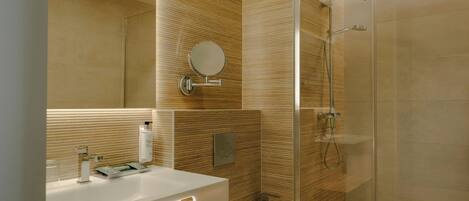 A modern bathroom with a glass shower enclosure, a white sink, and a mirror.