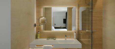 A modern bathroom with a large mirror, a shower, and a vanity with a sink.
