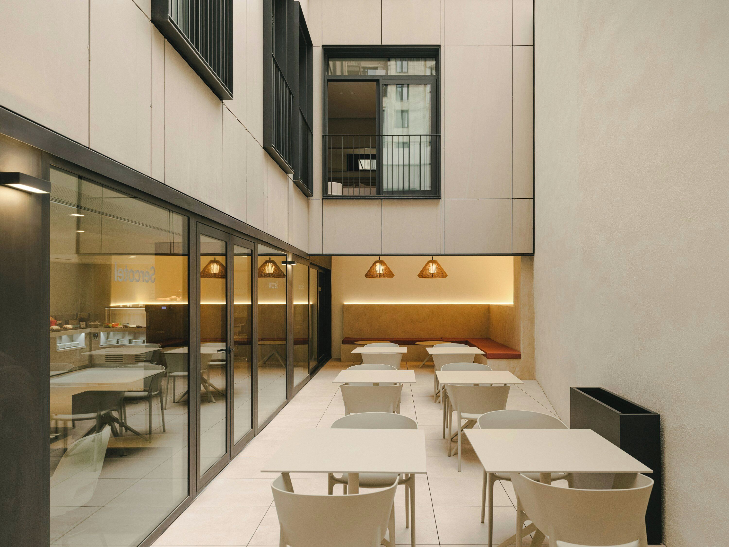 Un área de comedor moderna en interior con separadores de vidrio, mesas y sillas.