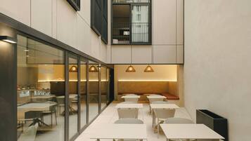 Un área de comedor moderna en interior con separadores de vidrio, mesas y sillas.