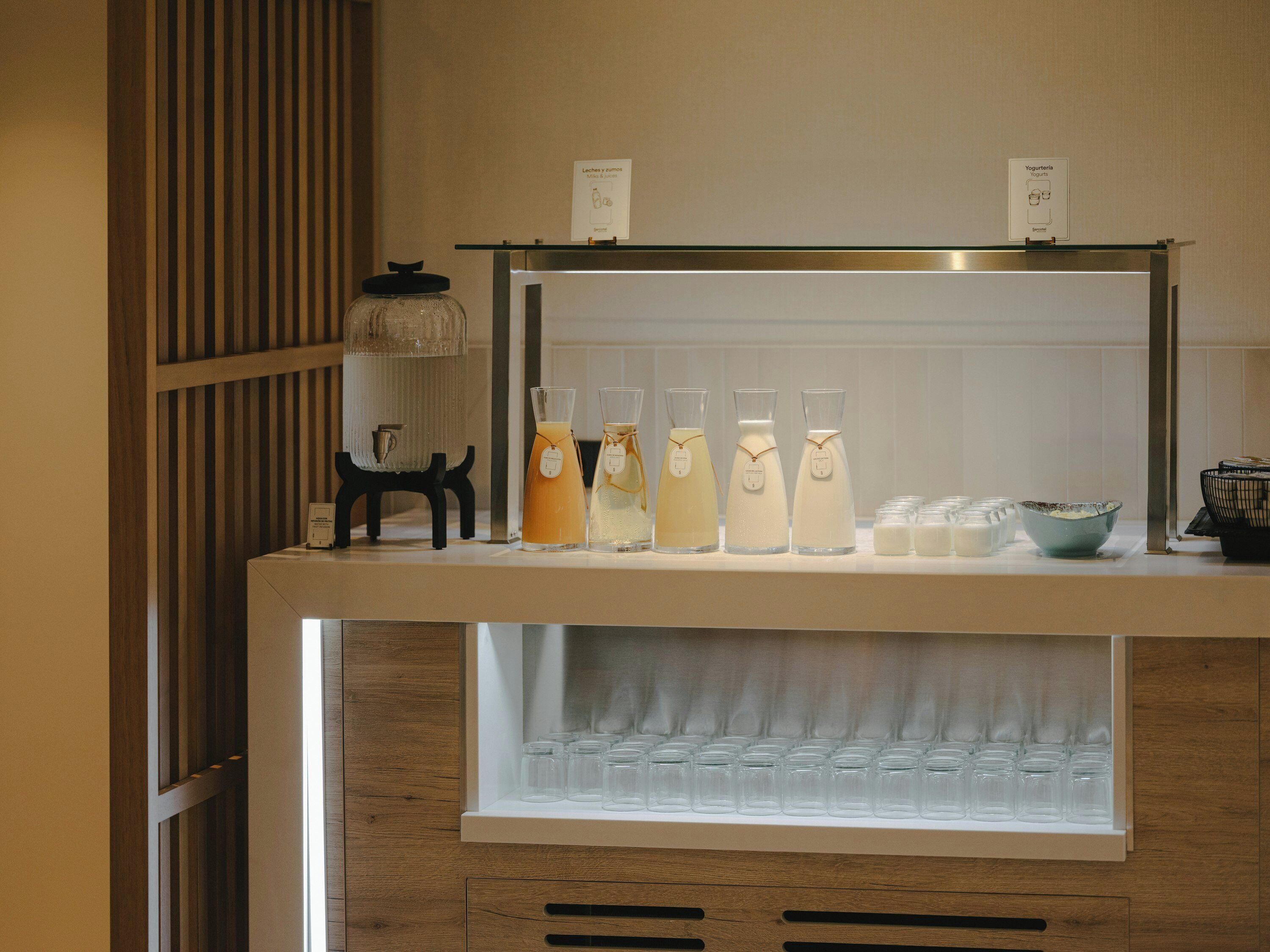 A beverage station with various drinks and a selection of glasses.