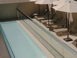 Zona de piscina con tumbonas y sombrillas.