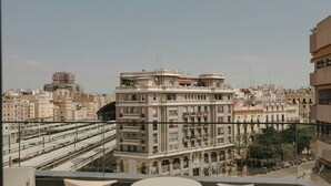 A terrace with a table and chairs, overlooking a cityscape with buildings and a train track. - Sercotel Valencia Ruzafa (Valencia)