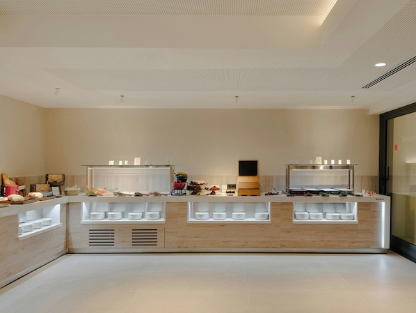A modern breakfast bar with a wooden finish, white plates, and a variety of food items.