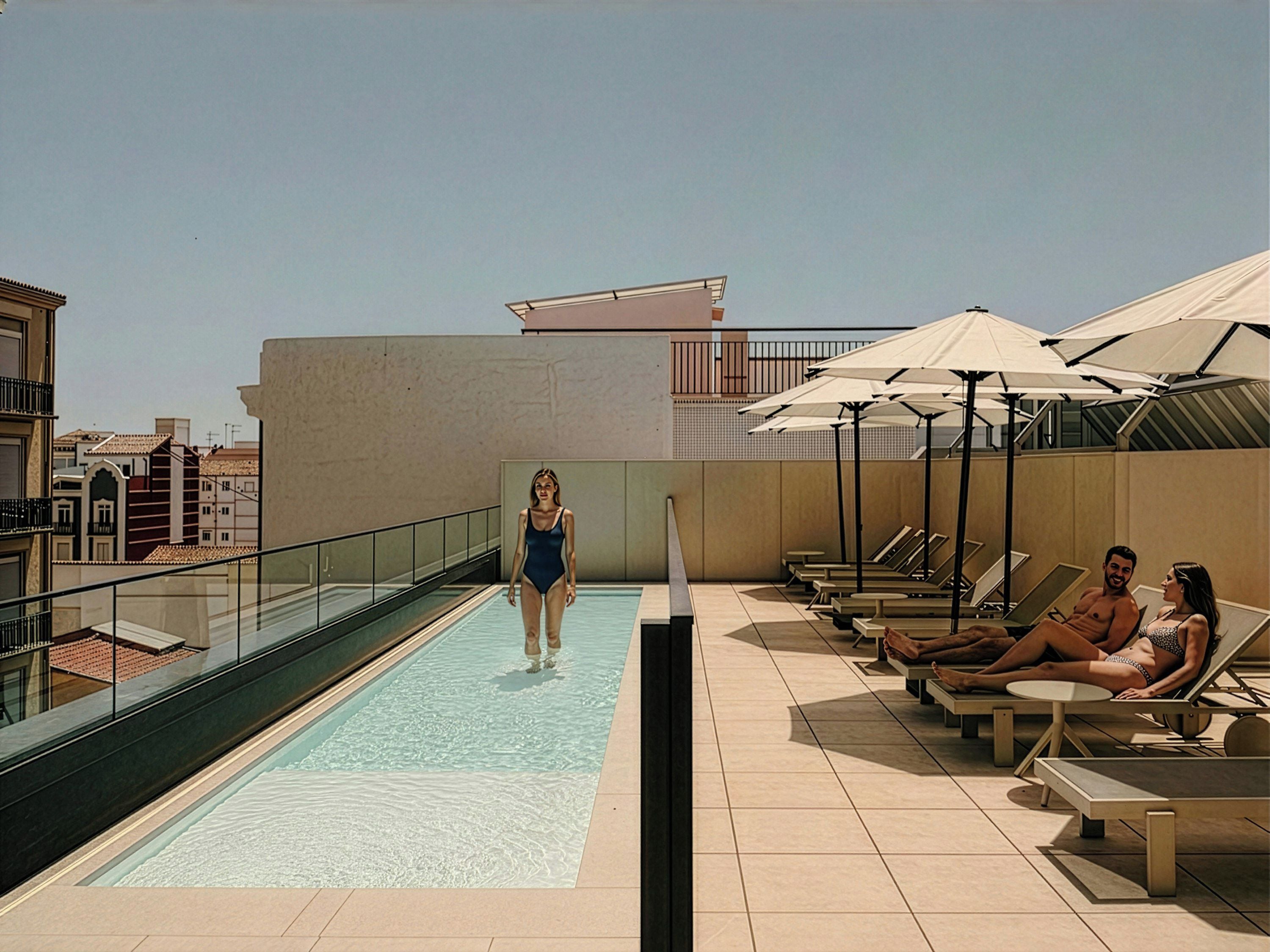 Un área de piscina en la azotea con vistas despejadas del paisaje urbano, tumbonas y sombrillas.