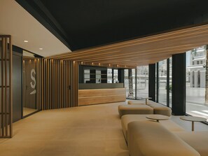 A modern reception area with a wooden slatted ceiling, a reception desk, and seating. - Sercotel Valencia Ruzafa (Valencia)