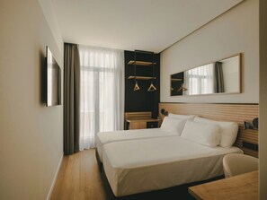 A hotel room with a double bed, a bedside table, a chair, a desk, a mirror, and a wardrobe with hanging clothes. - Sercotel Valencia Ruzafa (Valencia)
