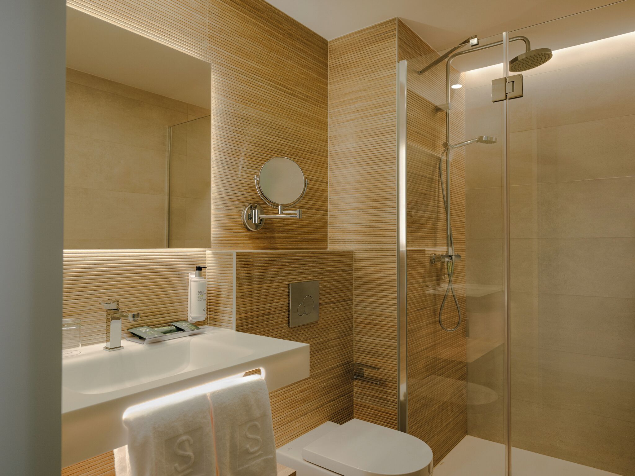 A modern bathroom with a glass shower enclosure, a white sink, and a toilet.