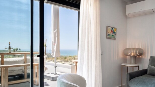 A modern room with a balcony, a chair, a table, and a lamp. - Ericeira Wave Nest by Lisbeyond (Carvoeira)