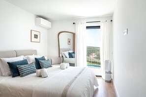 Ein Schlafzimmer mit einem großen Bett, einem Nachttisch, einem Spiegel und Blick auf einen Pool.