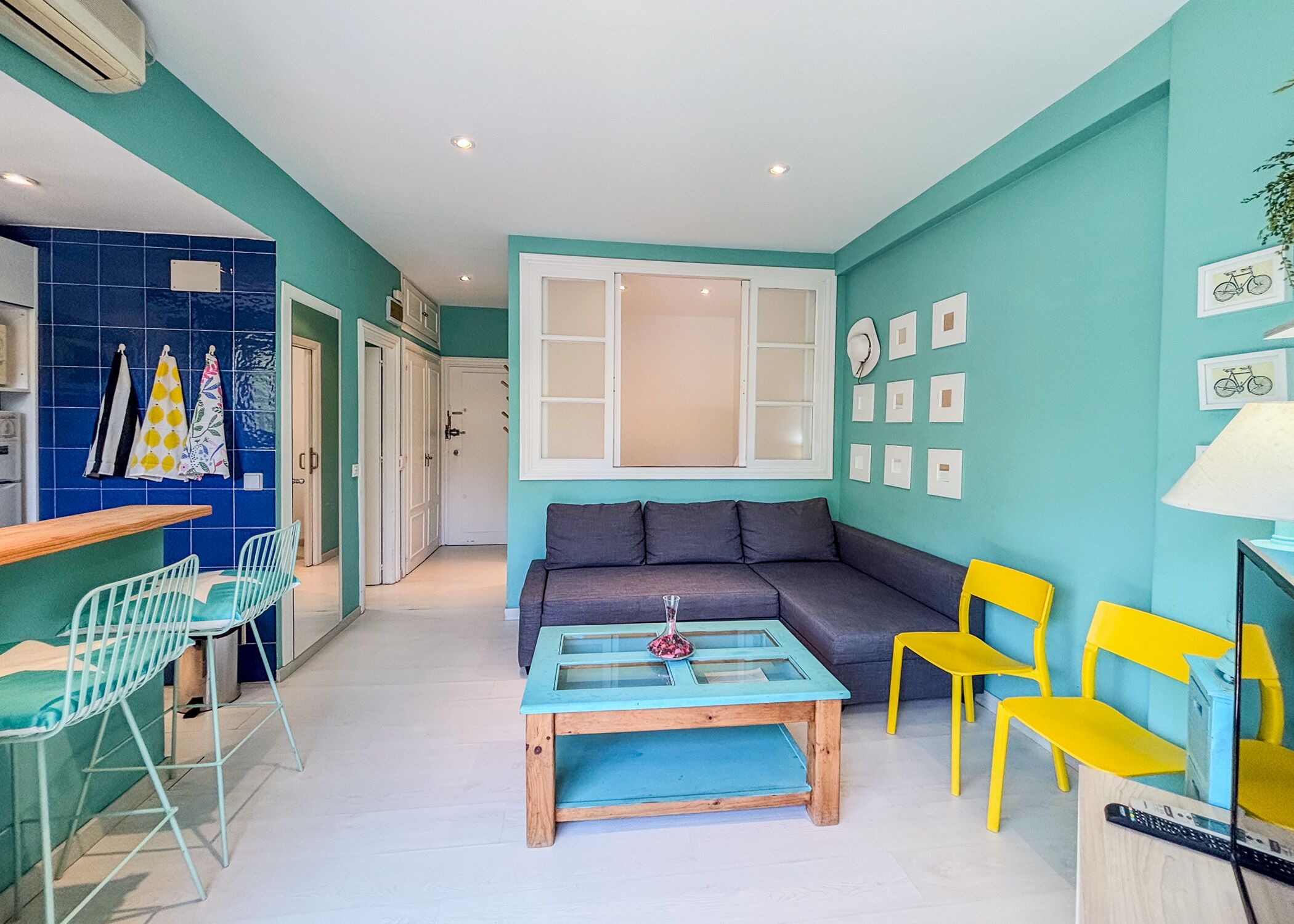 Un espacio habitable compacto con un sofá, una mesita de centro y una zona de comedor con sillas.