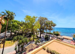 A coastal promenade with palm trees, a beach, and a clear blue sky. - Skol 225 –  Beachfront studio in Marbella | Terrace & Pool (Marbella)