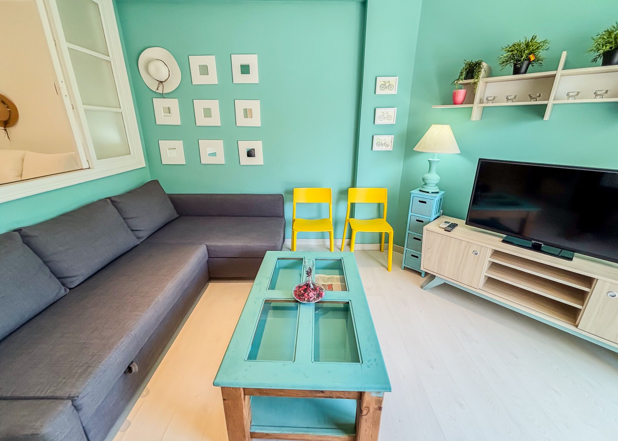 A living room with a sofa, two chairs, a coffee table, a TV, and wall decorations.