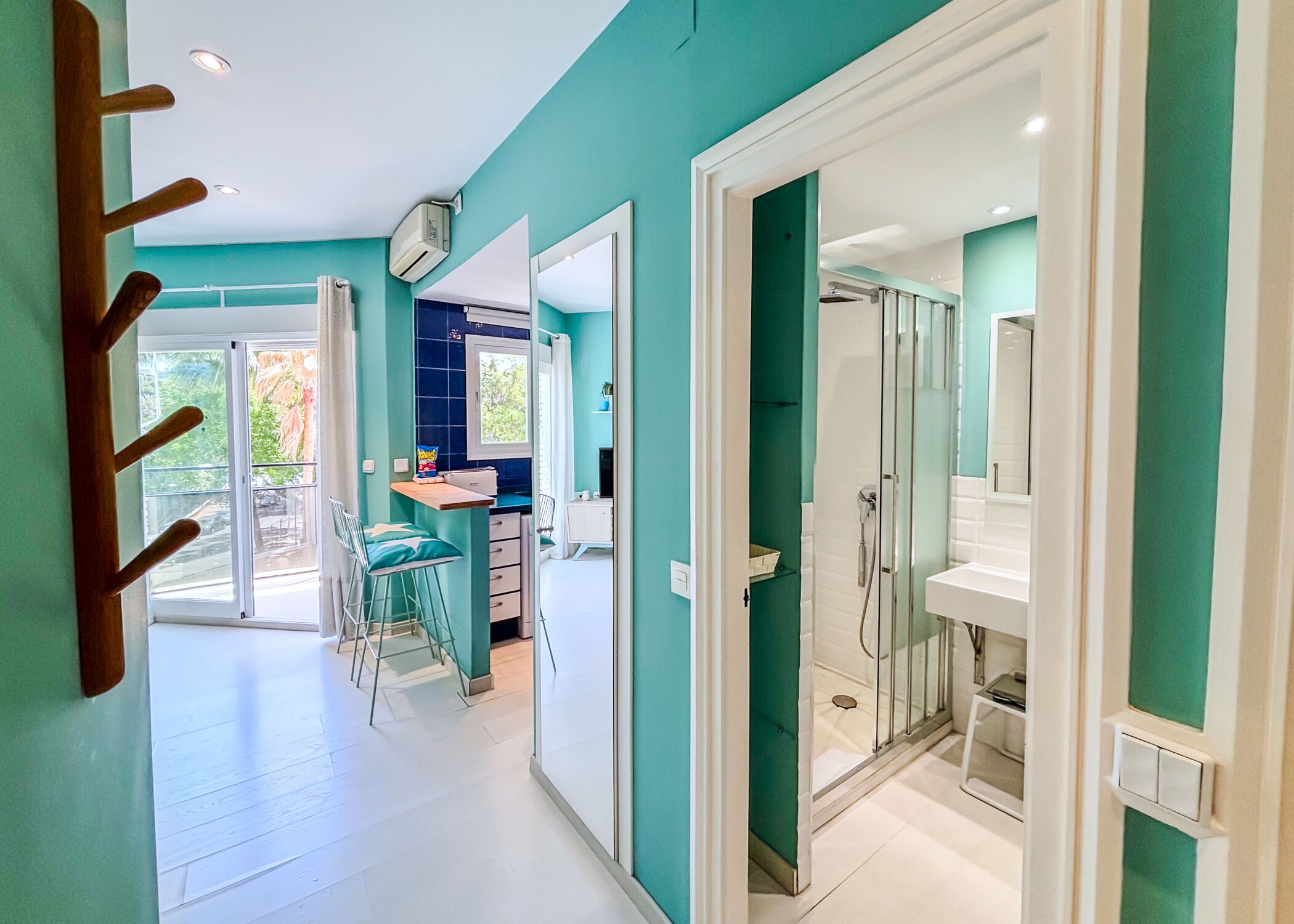 Eine moderne Küche mit Fenster, ein Essbereich mit Stühlen und ein Badezimmer mit Dusche.