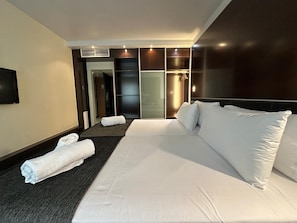 Una habitación de hotel con una cama grande, un televisor de pantalla plana en la pared y un vestidor con puertas correderas.