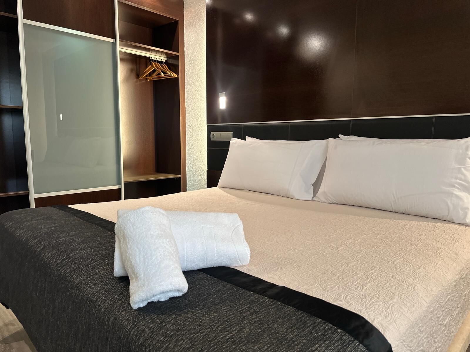 Una habitación de hotel con una cama, un armario y un espejo.