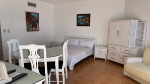 A bedroom with a bed, a small table with chairs, a cabinet, and two paintings on the wall. - Apartment in Albatros Club Resort, Juan Dolio (Playa Juan Dolio)