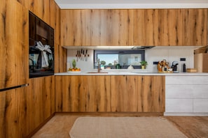 A modern kitchen with wooden cabinetry, a built-in oven, and a window above the sink. - Villa D  Briševo ZadarVillas (Briševo)